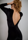Person wearing a black open-back dress against a plain background