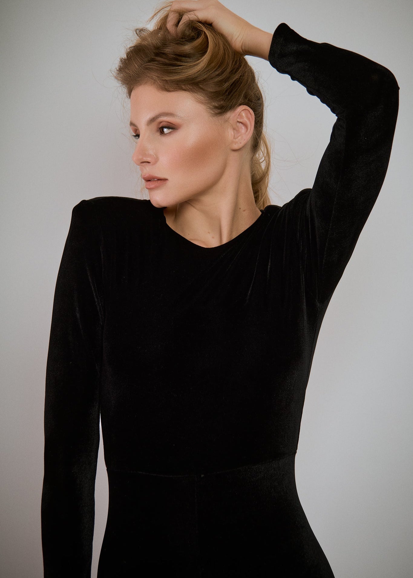 Woman in a black dress posing against a gray background