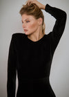 Woman in a black dress posing against a gray background