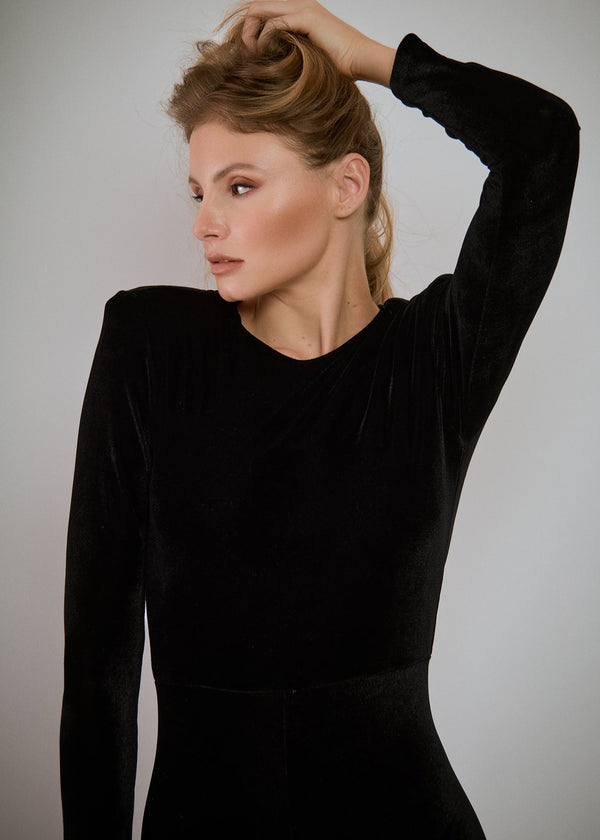 Woman in a black dress posing against a gray background