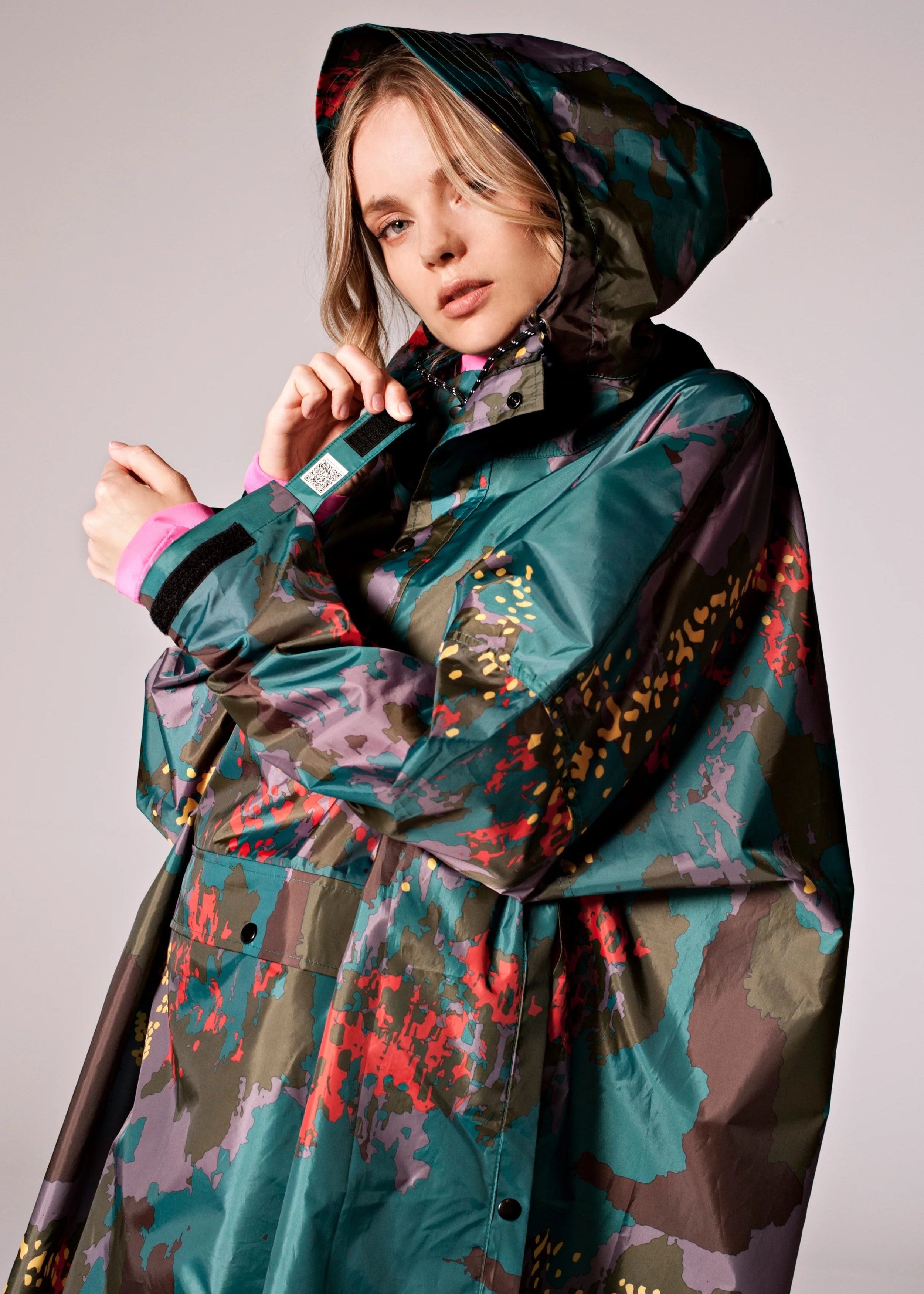Person wearing a colorful raincoat with a patterned design on a plain background