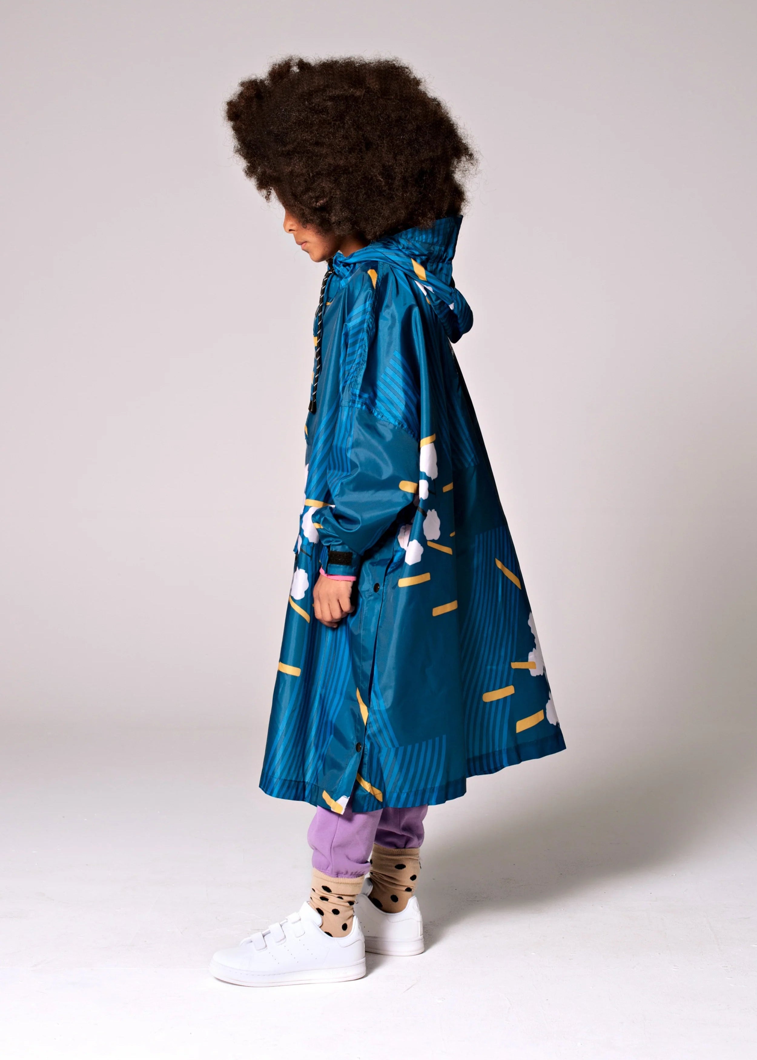 Person wearing a blue raincoat with white patterns on a plain background