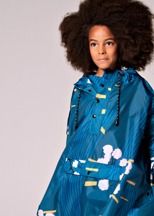 Child wearing a blue raincoat with white floral patterns on a gray background