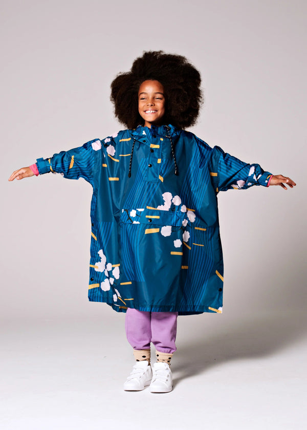 Child wearing a blue raincoat with white floral patterns on a plain background