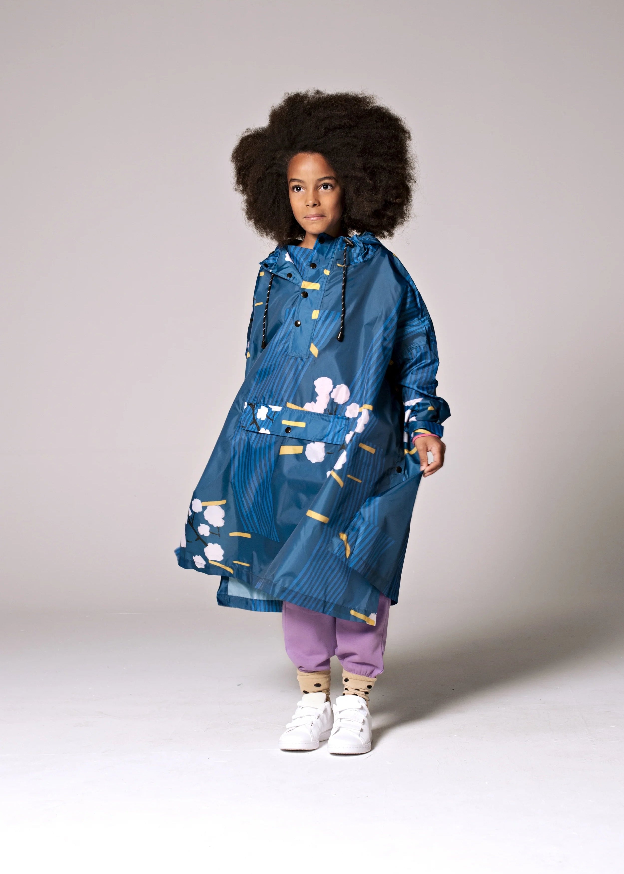 Person wearing a blue floral raincoat on a plain background
