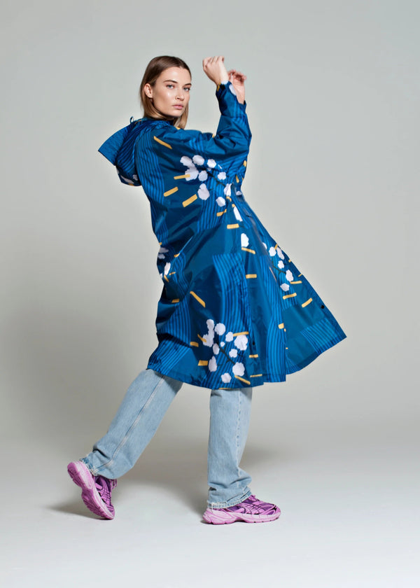 Woman wearing a blue dress with floral patterns on a plain background