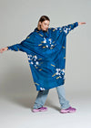 Person wearing a blue floral-patterned poncho on a plain background
