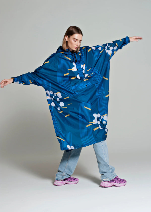 Person wearing a blue floral-patterned poncho on a plain background