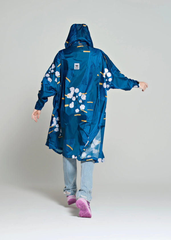 Person wearing a blue floral raincoat on a plain background
