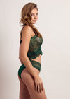 Woman wearing a green lace lingerie set on a plain background