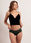 Woman wearing a black top and green lace underwear on a plain background