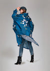 Person wearing a blue raincoat with floral pattern on a gray background
