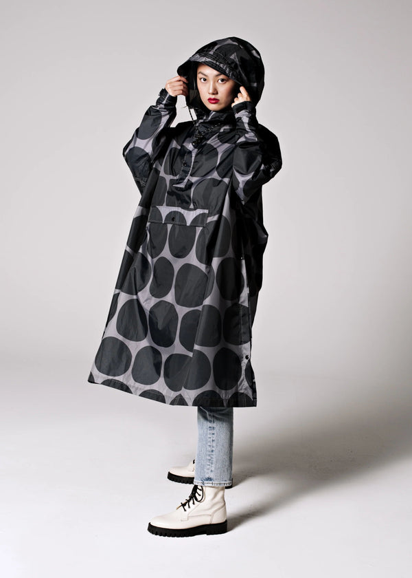 Person wearing a black and gray patterned raincoat on a white background