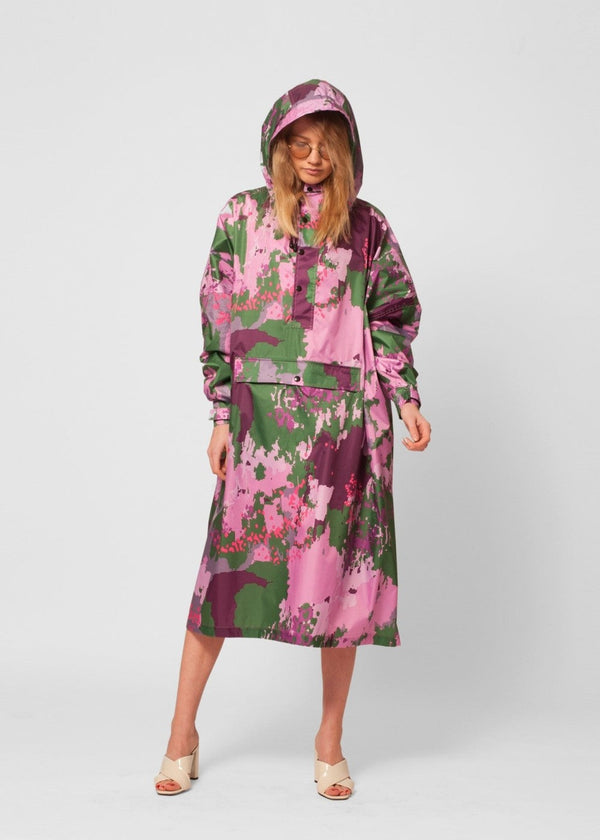 Person wearing a pink and green floral raincoat on a white background