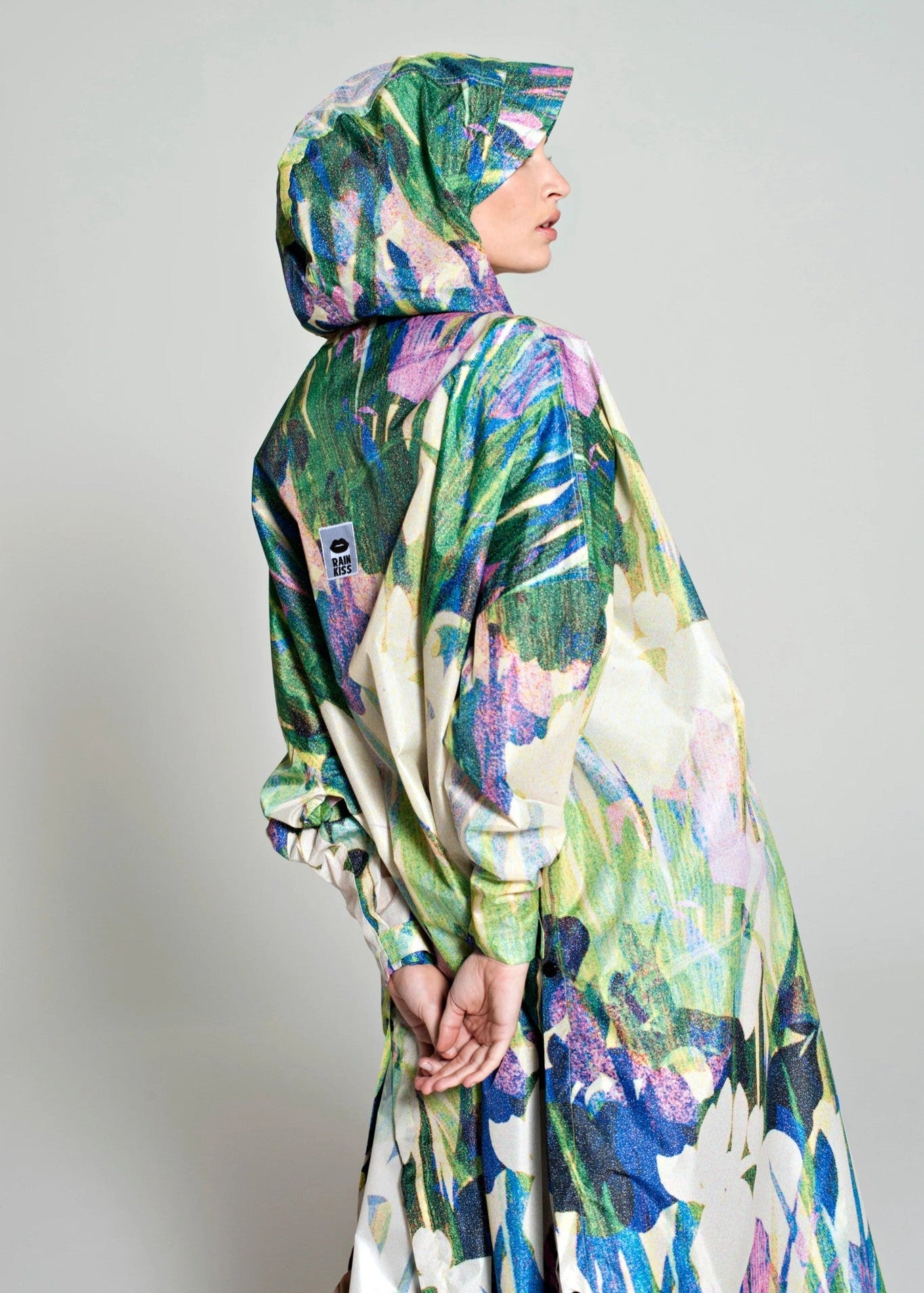 Person wearing a colorful floral-patterned raincoat against a plain background