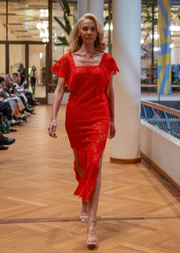 Woman in a red dress walking on a wooden floor with a blurred background