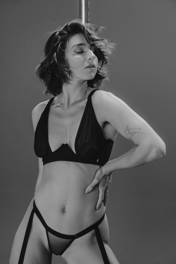 Black and white photo of a person wearing a black bikini against a neutral background