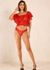 Woman wearing a red lace top and high-waisted red underwear on a beige background